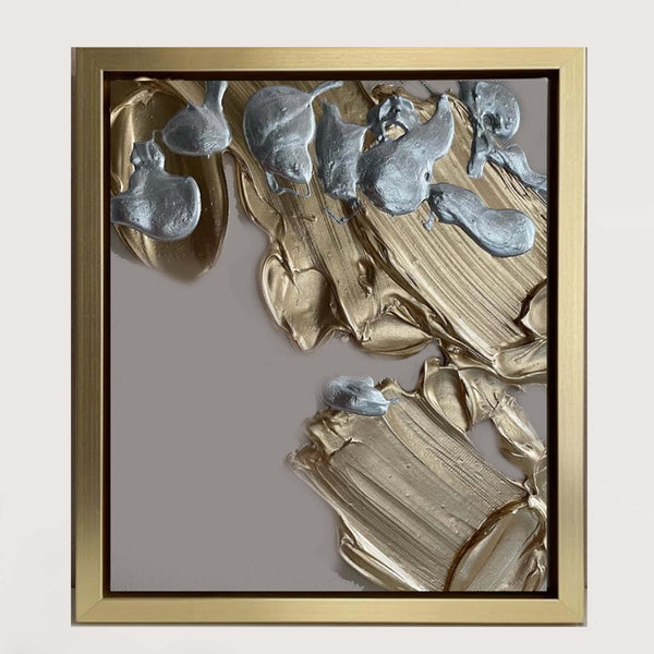 Abstract art piece with gold and silver colors in a gold frame on a gray background